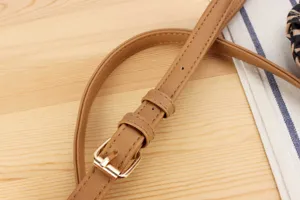 Detailed view of the stylish brown leather handbag strap with golden metal buckle design.