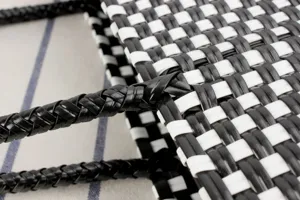 Dettaglio in primo piano della borsa di plastica intrecciata nera e bianca con manico.