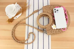 Handcrafted straw woven bag detail, elegant round handle crossbody design for summer beach vacation.