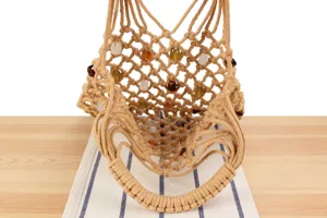 Close-up detailed view of hollow woven mesh tote bag with colorful beads, natural boho style.