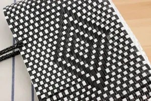 Primo piano della texture della borsa in plastica intrecciata nera e bianca, borsa estiva.
