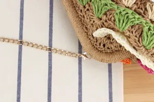 Vista dettagliata della borsa intrecciata a mano elegante con tracolla a catena dorata casual.
