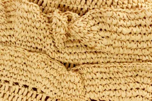Close-up detail of beige handmade woven straw bag texture, showing exquisite craftsmanship.
