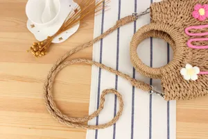 Detail shot of handmade woven straw crossbody bag with floral decor, natural beach style fashion.