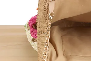 Borsa in paglia intrecciata a mano, dettaglio interno con fodera e catena metallica dorata.