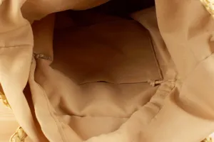 Interior detail view of casual women woven handbag with khaki fabric lining and pocket storage.
