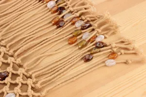 Close-up shot of woven macrame handbag fringe featuring detailed colorful beads.