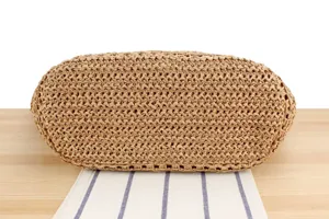 Detailed view of the bottom of a woven straw shoulder bag, natural fiber texture and design.