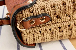Nahaufnahme der Strohgeflecht Handtasche mit braunem Lederbesatz und goldenem Metall.