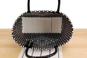 Vista dettagliata dell'interno del cesto in plastica intrecciata nera e bianca, struttura.