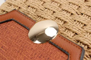 Nahaufnahme Detail der Strohgeflochtenen Handtasche mit braunem Lederaufnäher und Goldschnalle.