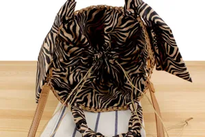 Detailed view of the woven straw bucket bag interior, zebra print lining and drawstring.