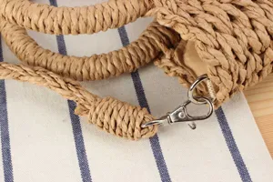 Detailed view of handmade woven straw handbag strap and metal clasp, perfect for summer beach.