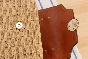 Geflochtene Strohhandtasche Detail zeigt strukturierten Strohkörper und Lederklappe.
