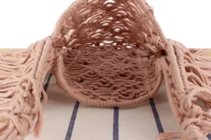 Handcrafted pink macrame woven bag detail view, showing intricate knotting and bottom structure.