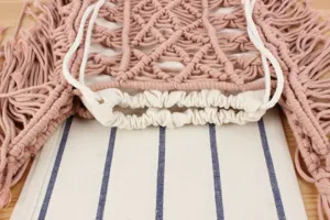 Handmade pink macrame woven bag detail view, showing delicate cotton cord knots and lining.
