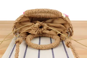 Close-up detail of woven straw handbag interior with fabric drawstring lining and round handles.