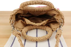Detailed view of the woven straw handbag interior with lining and metal hardware hooks.