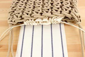 Handmade woven rope shoulder bag detail showing textured knot design and pouch lining.