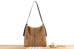 Gros plan détaillé du sac à bandoulière en paille tressée à la main avec une texture fine.