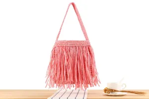 Vue rapprochée du détail du sac bandoulière en franges tissées roses, accessoire chic.