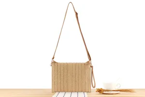 Close-up detail of the woven straw crossbody bag featuring vertical texture and delicate strap.
