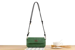 Detail view of a stylish green hollow woven crossbody bag featuring a black leather strap.