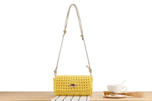 Detailed view of the yellow hollow woven shoulder bag, featuring delicate mesh and thin strap.
