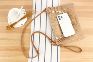 Straw woven crossbody clutch bag with fringe and shell decor, detailed view showing texture.