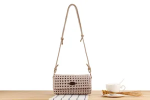 Beige woven crossbody bag detail, intricate lattice pattern, adjustable strap and metal hardware.