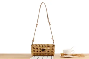 Detailed view of the tan woven crossbody bag with metal plaque, showcasing texture and hardware.