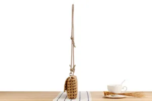 Detailed side view of stylish woven crossbody bag on a wooden table with cafe props.