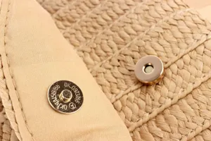 Close-up detail of straw woven bag magnetic snap hardware showcasing craftsmanship.