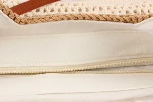Close-up detail of cream canvas inner lining and zipper closure in woven straw handbag.