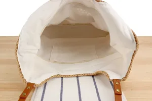 Interior detail view of a woven straw shoulder bag with white fabric lining and inner pocket.