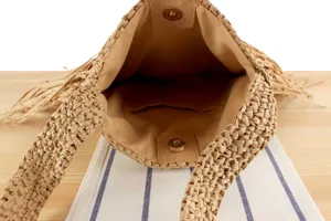 Vue detaillee de l interieur du sac a main en paille tressee avec doublure et pression.