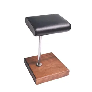 Horloge display standaard met houten basis, chroom stang en zwart lederen kussen op tafel.