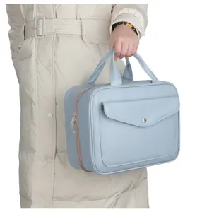Detailed view of light blue travel cosmetic bag with dual handles and front pocket storage.