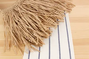 Detail du sac a main en paille a franges montrant une texture naturelle et elegante.