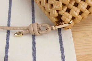 Close-up of stylish woven shoulder bag with delicate texture and elegant metal hardware.