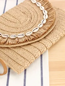 Chic straw woven crossbody bag featuring natural cowrie shells, ideal for summer beach trip.