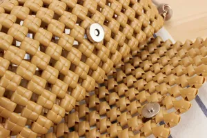 Close-up detail of stylish hollow woven handbag texture with metal magnetic snap button.