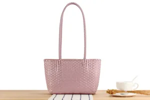 Pink woven plastic tote bag detail view, casual beach vacation picnic basket minimalist style.