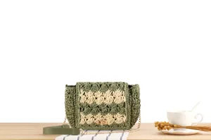 Detailed view of the green and beige woven straw shoulder bag with elegant gold chain strap.