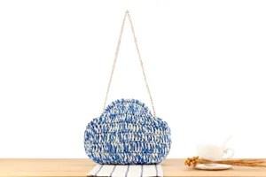 Detailed view of the blue and white woven handbag, showing the textured straw pattern and chain.