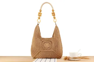 Borsa a spalla in paglia lavorata all'uncinetto con perline di legno per vacanze estive.
