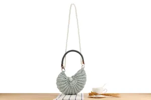 Handcrafted crochet seashell bag detail, pearl chain strap and dark handle for casual daily use.