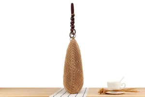 Vista dettagliata di borsa a tracolla intrecciata a mano con manico in perline di legno e paglia.