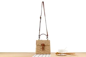 Handmade woven straw crossbody bag with brown leather handle and cute front buckle detail.