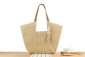 Detailed close-up of the stylish straw woven tote bag with brown leather handles and chic tassel.